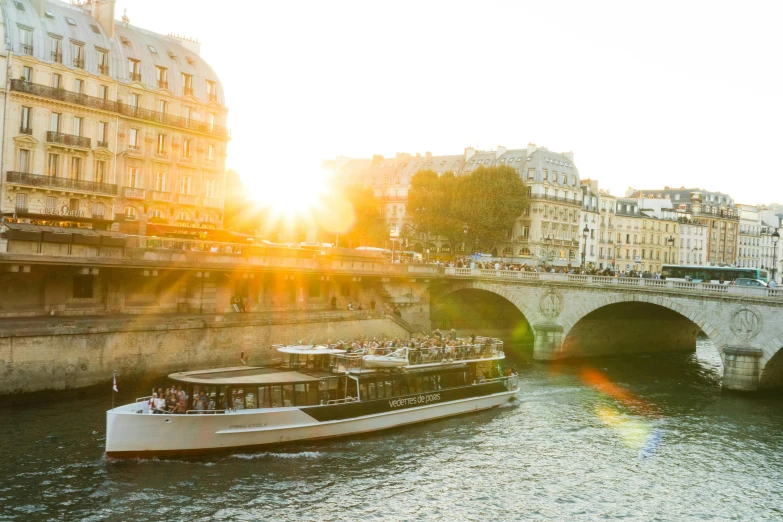 a boat traveling down a river next to a bridge, by Julia Pishtar, pexels contest winner, art nouveau, golden sunlight, paris hotel style, olafur eliasson, group photo