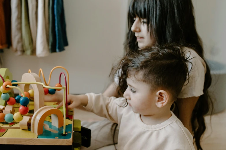 a woman and a child playing with wooden toys, pexels contest winner, looking across the shoulder, profile image, charli bowater and artgeem, attractive photo