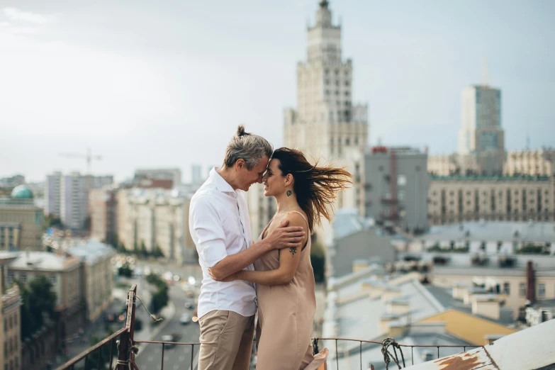 a man and a woman standing on top of a building, by Emma Andijewska, pexels contest winner, neo-romanticism, russian girlfriend, with stalinist style highrise, al fresco, embracing