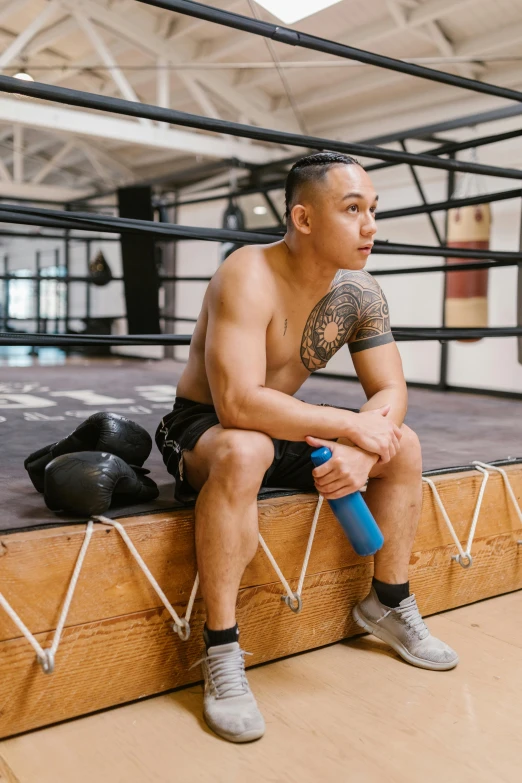 a man sitting on a platform in a boxing ring, inspired by Eddie Mendoza, justin sun, local gym, profile image, lgbtq