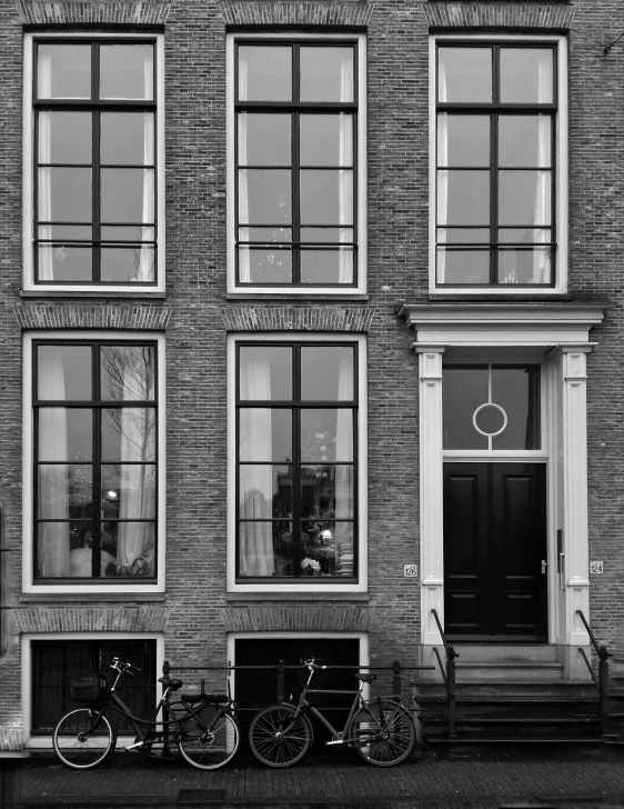 a black and white photo of bicycles parked in front of a building, by Jan Gregoor, dutch angle digital art, tall door, bay window, by joseph binder