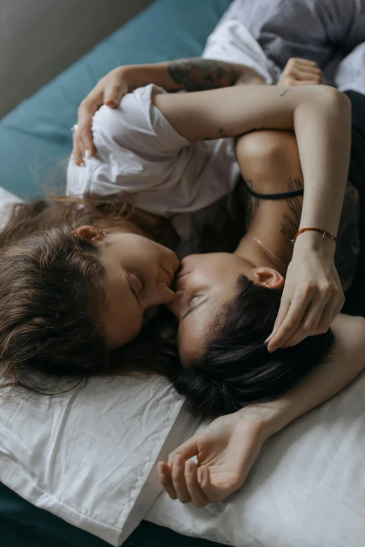 a woman laying on top of a bed next to a man, trending on pexels, romanticism, portrait of two girls kissing, lesbian embrace, woman holding another woman, high angle