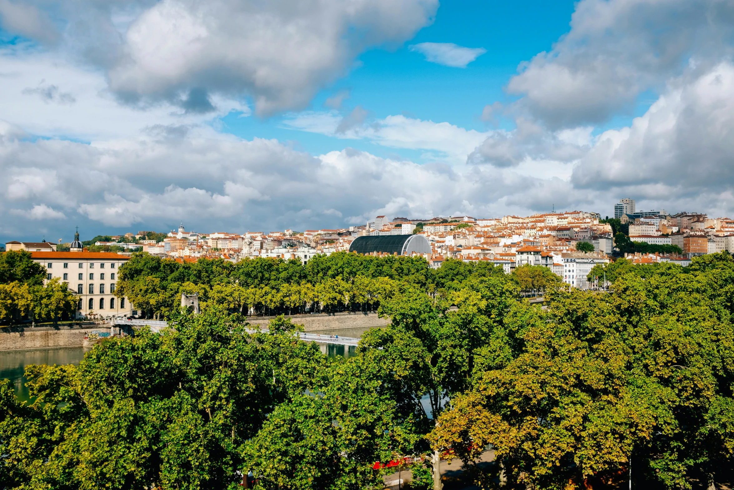 a view of a city from the top of a hill, by Juan Giménez, on a bright day, square, landscape photo, multicoloured