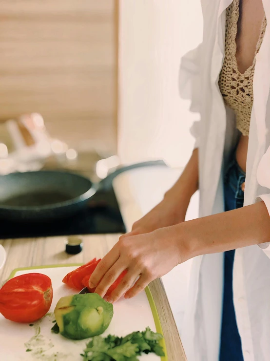 a woman chopping vegetables on a cutting board, by Julia Pishtar, pexels contest winner, wearing long white robe, gif, low quality photo, good looking