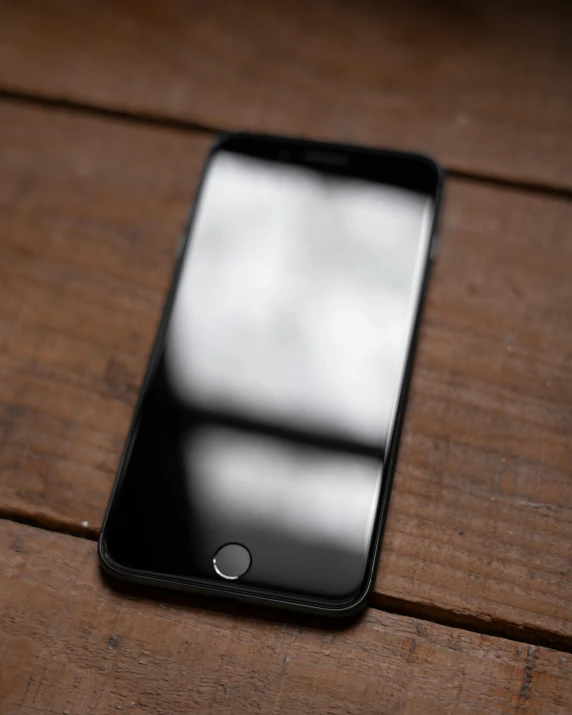 a cell phone sitting on top of a wooden table, a picture, by Robbie Trevino, unsplash, gradient black to silver, square, translucent body, thumbnail
