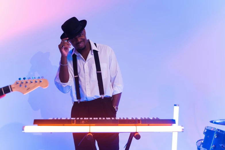 a man standing next to a keyboard on a stage, inspired by Richard Wright, pexels, wearing a top hat, vibrant lights, in front of white back drop, black man