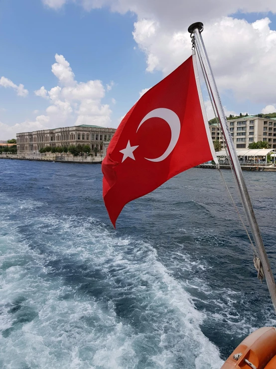 a red and white turkish flag on a boat, pexels contest winner, thumbnail, low quality photo, river in the background, profile image