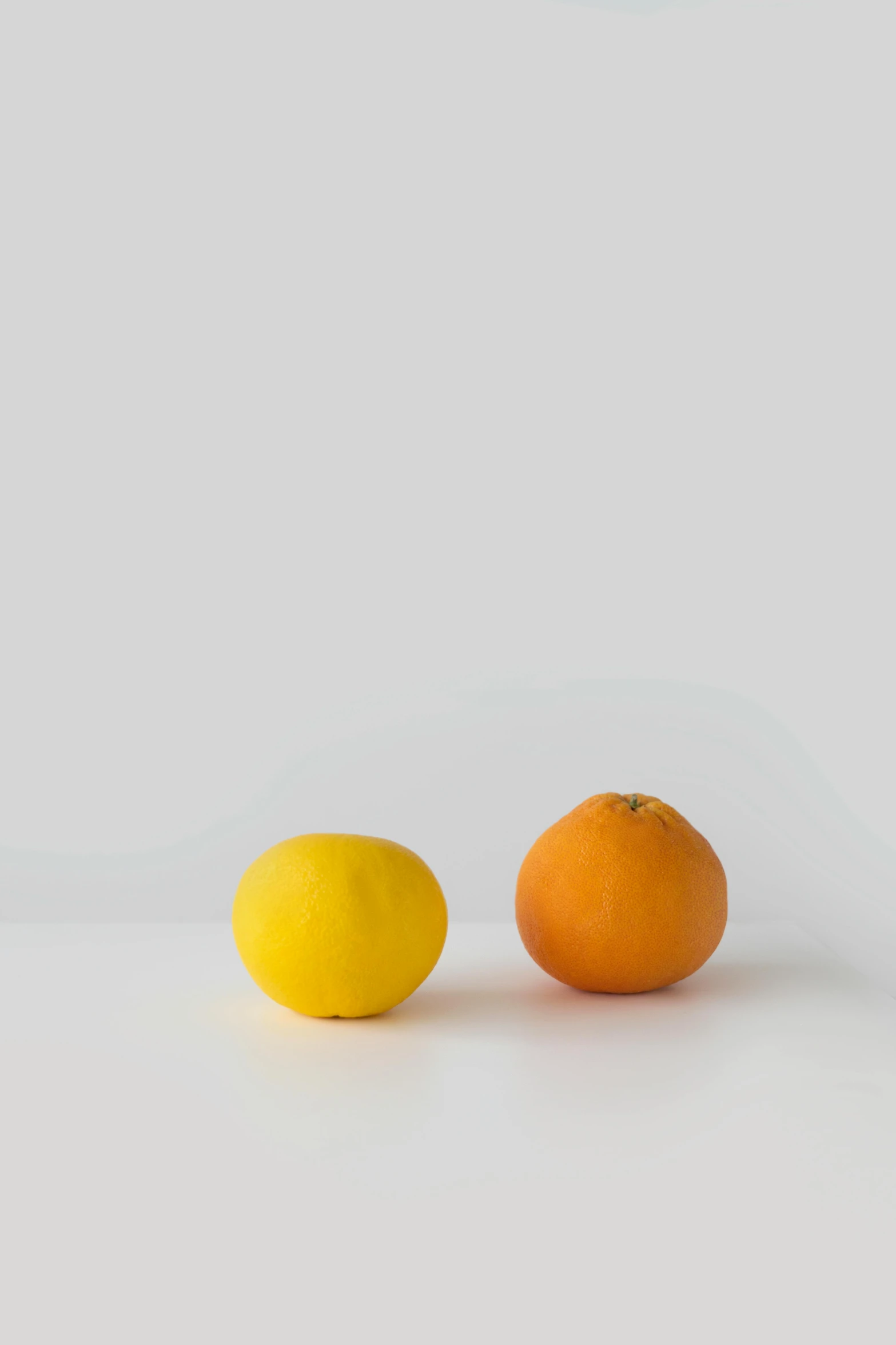 two oranges and a lemon on a white surface, a still life, unsplash, minimalism, 2010s, standing still, portrait of small, organic color