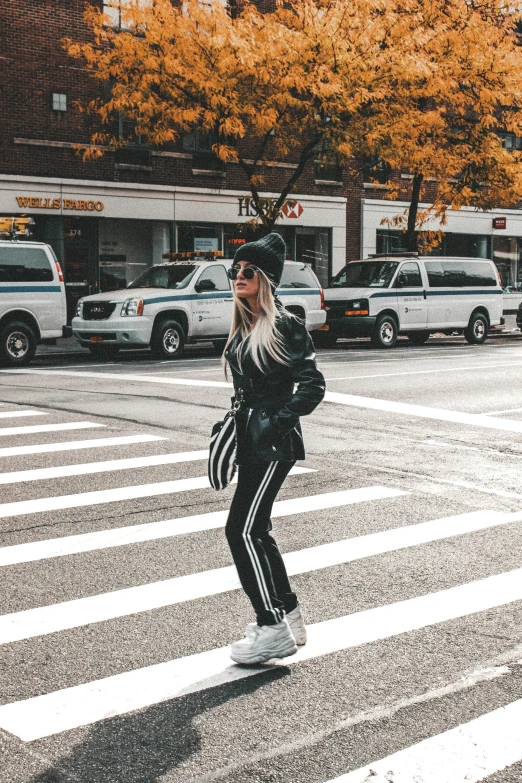 a woman crossing the street in a black and white outfit, trending on pexels, man in adidas tracksuit, kailee mandel, 🚿🗝📝, street of new york