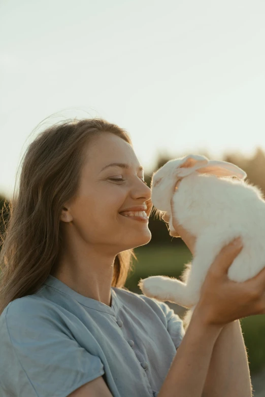 a woman holding a white rabbit in her hands, pexels contest winner, at the golden hour, smiling playfully, profile image, human lamb hybrid