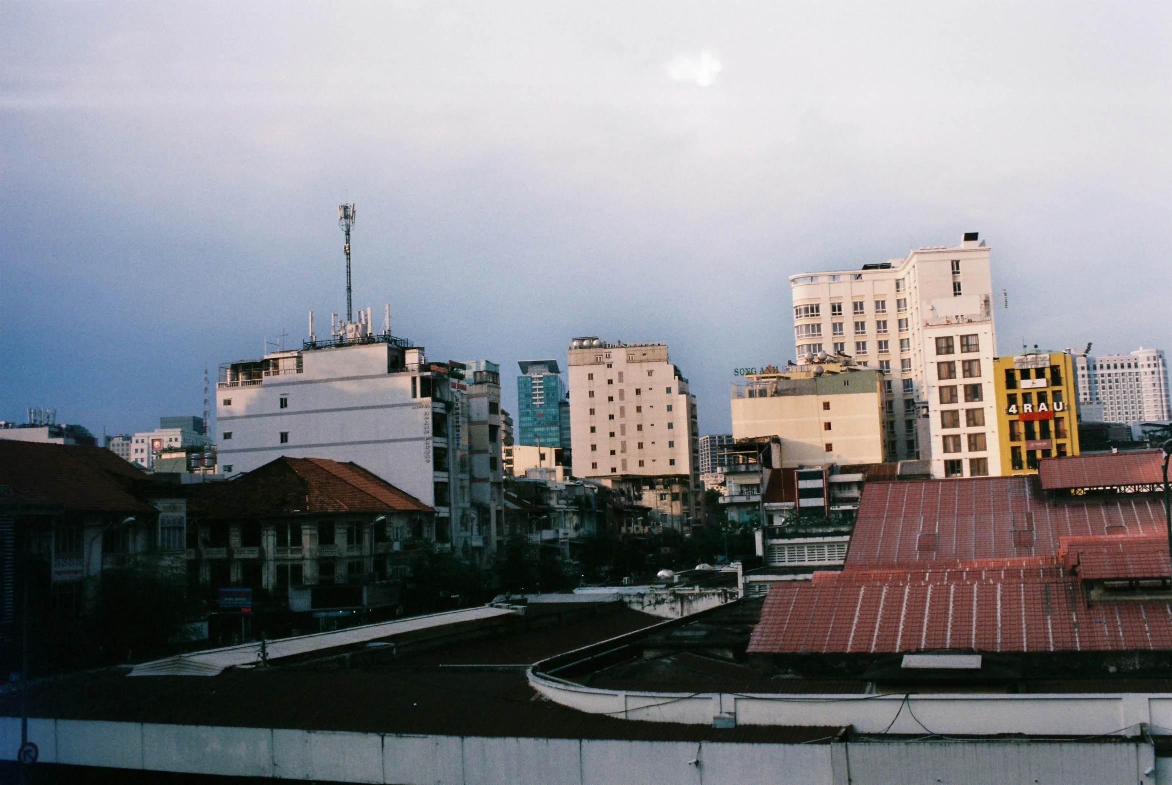 a view of a city from the roof of a building, an album cover, unsplash, brutalism, vietnam, low quality photo, early evening