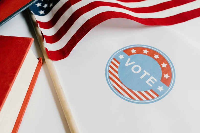 a book sitting on top of a table next to an american flag, election poster, miscellaneous objects, profile image, featured