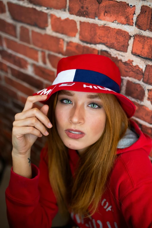 a woman sitting in front of a brick wall wearing a red hat, russian flag, pewdiepie, eleanor tomlinson, bucket hat