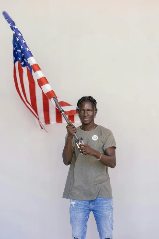 a woman holding an american flag in front of a white wall, by Alison Geissler, adut akech, taken in the late 2010s, androgynous male, awarded winning photo