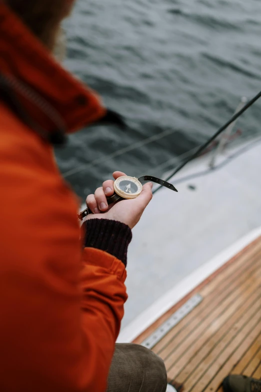 a man holding a fishing rod on a boat, by Jan Tengnagel, unsplash, holding gold watch, wind rose, high-quality photo, icon