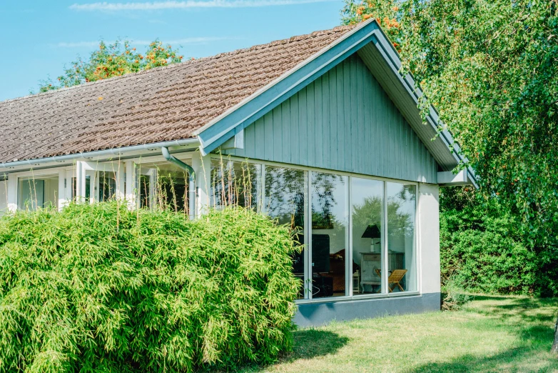 a house sitting in the middle of a lush green yard, by Jesper Knudsen, unsplash, bauhaus, profile image, william eggleston style, chalet, floor - to - ceiling windows