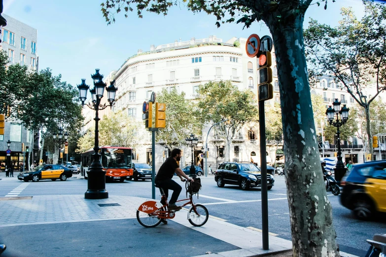 a person riding a bike on a city street, inspired by Tomàs Barceló, pexels contest winner, square, lush surroundings, philippe starck, spanish