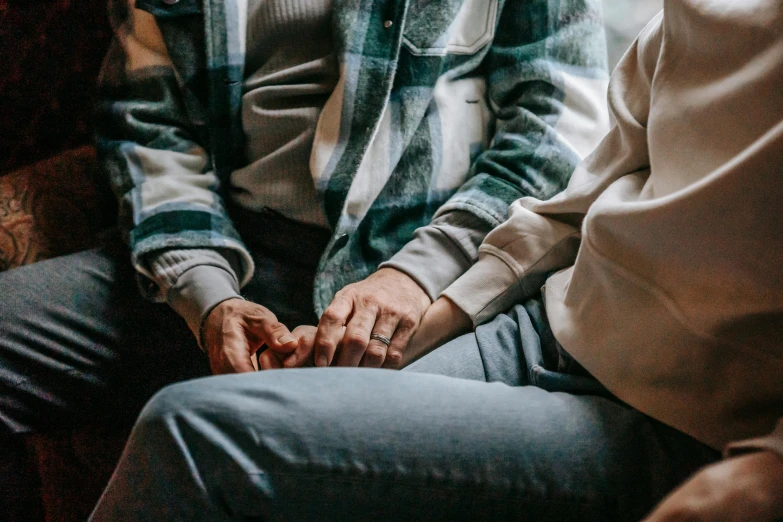 a man and a woman sitting next to each other, trending on pexels, holding each other hands, lesbian, sitting in an armchair, wearing casual clothes