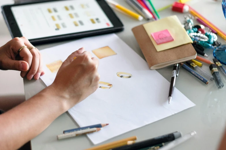 a person sitting at a table working on a piece of paper, a drawing, trending on pexels, logo design, 9 9 designs, gilding, rectangle