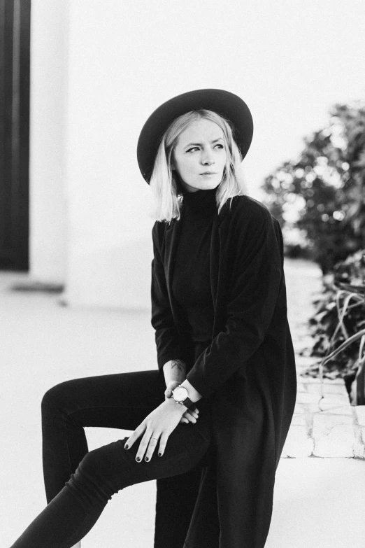 a black and white photo of a woman sitting on a bench, by Sara Saftleven, tall hat, black outfit, aurora aksnes, wearing turtleneck