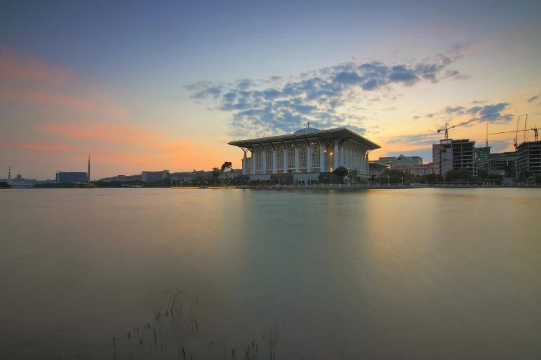 a large building sitting on top of a lake, by Basuki Abdullah, unsplash contest winner, neoclassicism, malaysian, cai guo-qiang, dawn and dusk, on a great neoclassical square