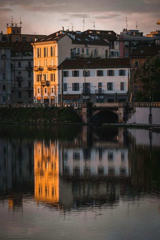 a body of water with buildings in the background, pexels contest winner, renaissance, light reflection, bizzaro, late summer evening, two stories