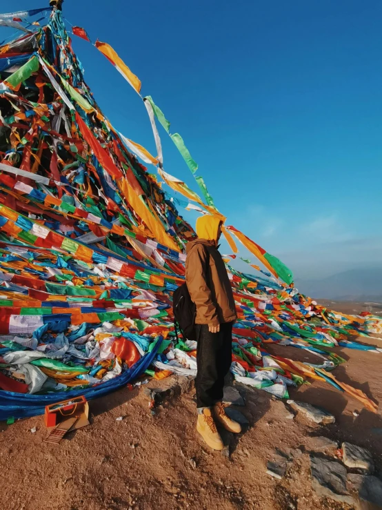 a man standing in front of a pile of clothes, inspired by Steve McCurry, trending on unsplash, prayer flags, mongolia, panorama shot, taken on an iphone