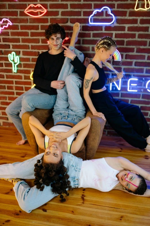 a group of people sitting on top of a wooden floor, inspired by Nan Goldin, trending on pexels, neon signs in background, lesbians, pixeled stretching, cutecore