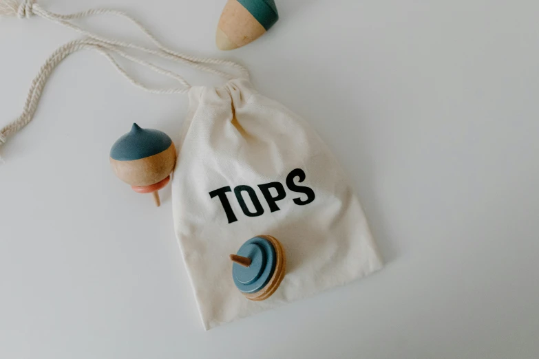 a bag filled with wooden toys sitting on top of a table, by Toss Woollaston, topknot, minimalistic logo, domes, grey and blue theme
