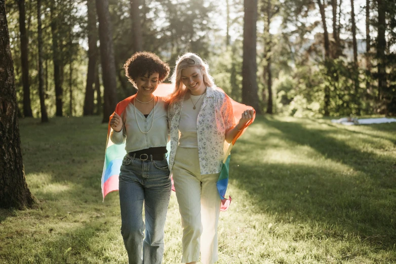 a couple of women walking across a lush green field, pexels, lgbt, bright light, college girls, a colorful