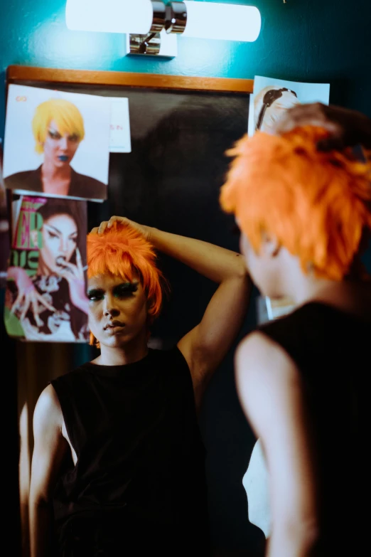 a woman with orange hair standing in front of a mirror, an album cover, trending on pexels, androgyny, mohawks, performance, behind the scenes photo