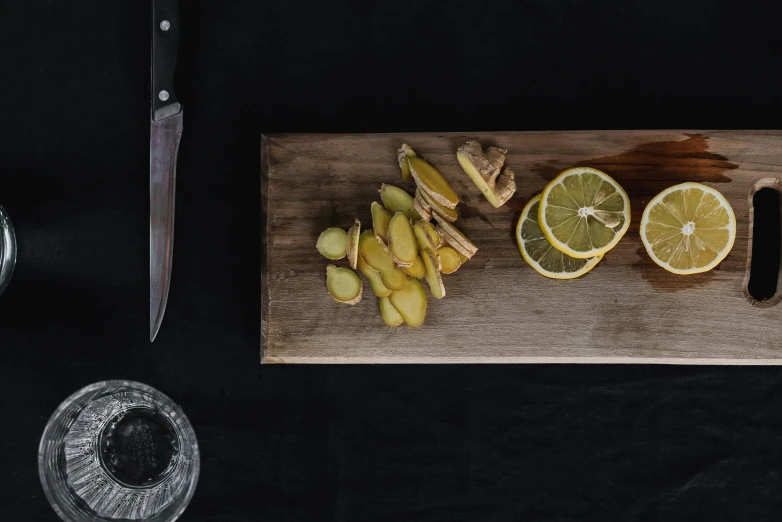 a wooden cutting board topped with sliced lemons, a still life, inspired by Kanō Shōsenin, unsplash, severed limbs, panoramic shot, plated arm, three quarter shot