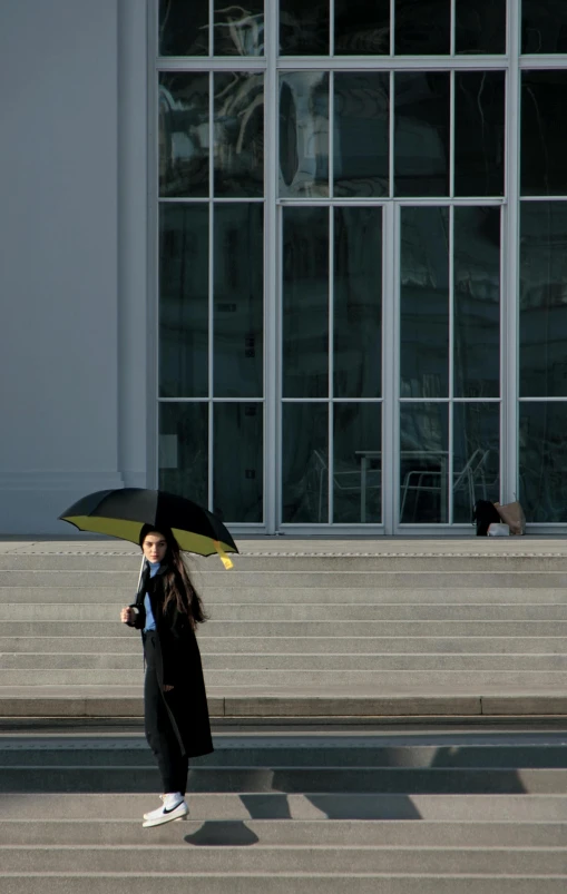 a woman walking down a set of stairs with an umbrella, a picture, unsplash, berlin secession, photographed for reuters, a man wearing a black jacket, ap, schools