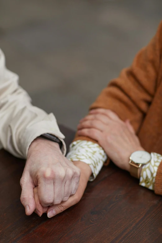 a close up of two people holding hands, by Jan Tengnagel, unsplash, renaissance, sitting on a mocha-colored table, watch photo, arms folded, amanda lilleston