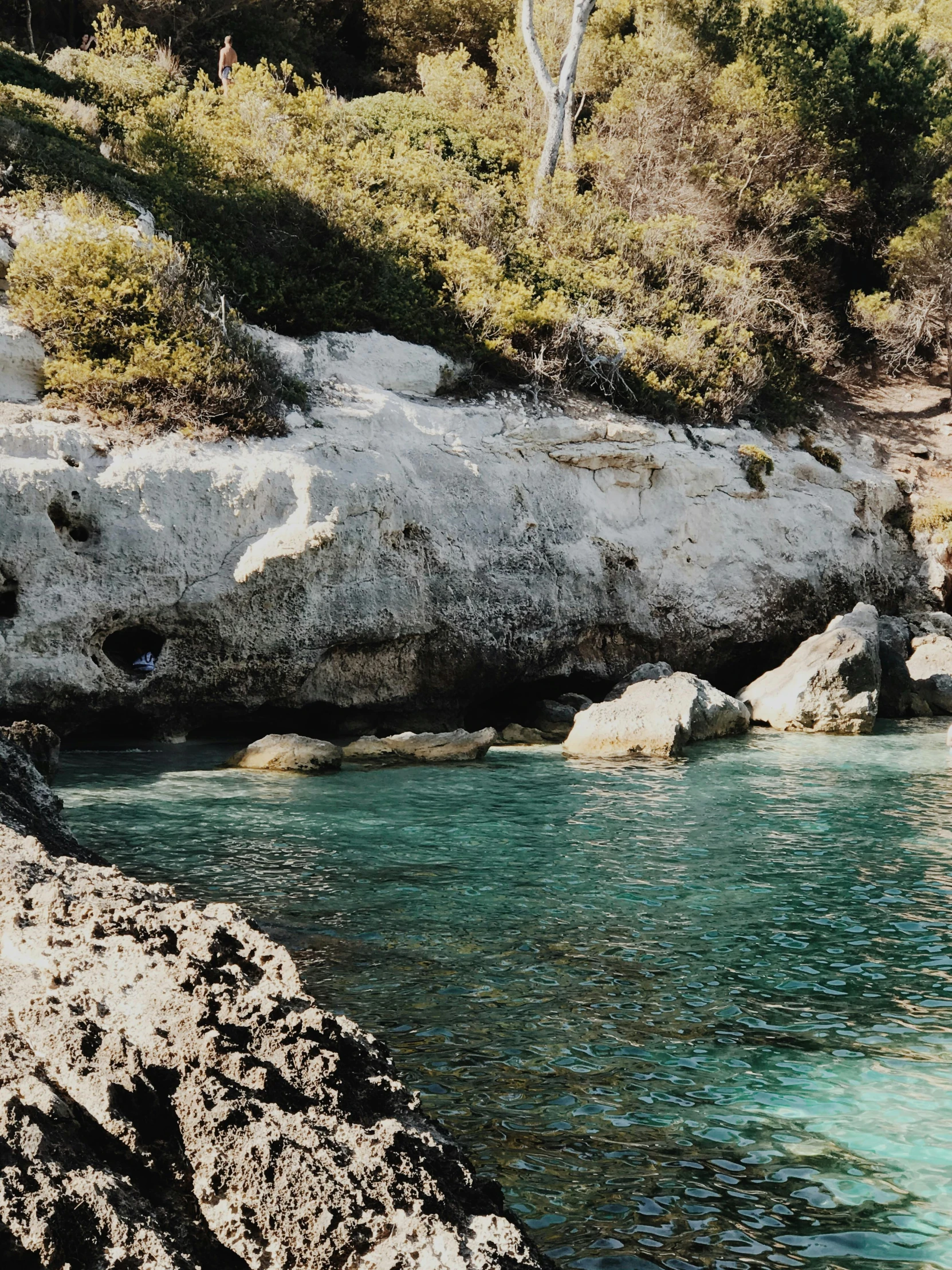 a man standing on top of a rock next to a body of water, turquoise water, grotto, traditional corsican, beautiful screenshot