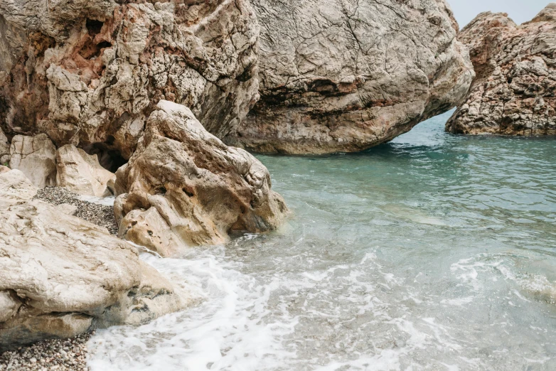 a man riding a surfboard on top of a rocky beach, pexels contest winner, romanticism, hotspring hidden in a cave, costa blanca, inside a marble, 2 5 6 x 2 5 6 pixels