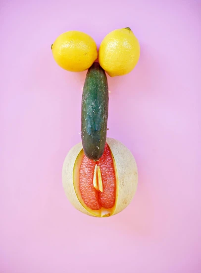 a cucumber, lemons, and a cucumber are arranged in the shape of a man's face, a surrealist sculpture, inspired by Ren Hang, trending on pexels, magic realism, barbie doll in panties and bra, pink and yellow, opening shot, body builder