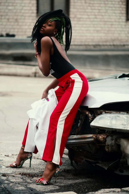 a woman sitting on the hood of a car, trending on pexels, auto-destructive art, stripey pants, dark skin, red white black colors, wearing off - white style