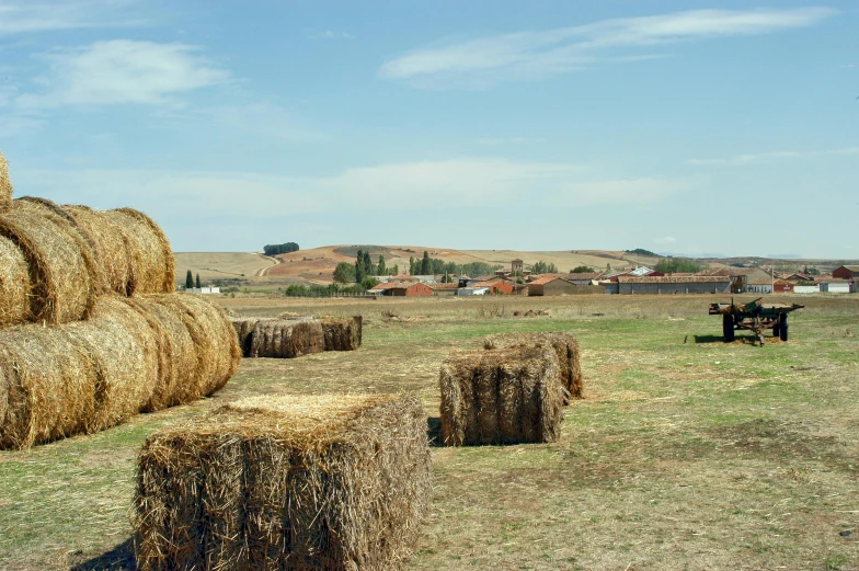 hay bales stacked on top of each other in a field, an album cover, unsplash, land art, patagonian, countryside city scene, 2000s photo, high-resolution photo