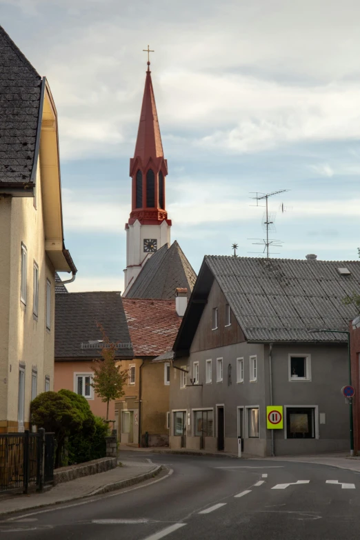 a street with buildings and a steeple in the background, hardturm, suburb, red roofs, from street level