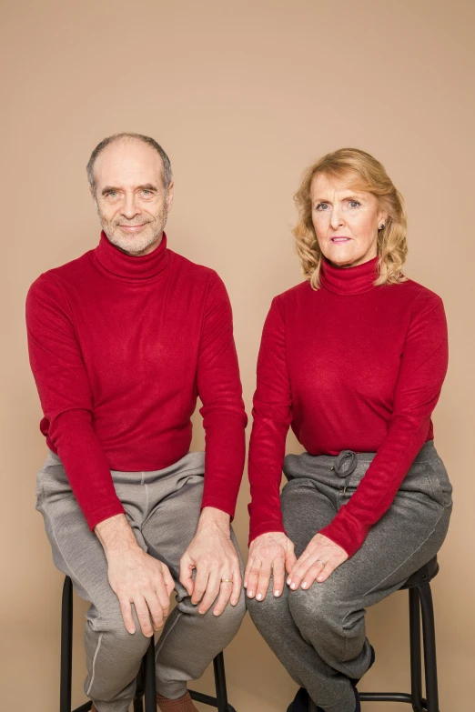 a man and a woman sitting next to each other, red sweater and gray pants, symmetrical image, lynn skordal, portrait image