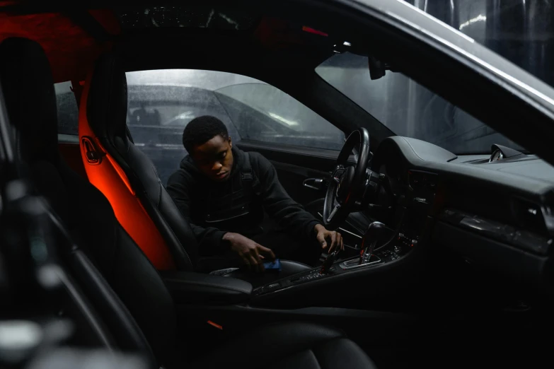 a man sitting in the driver's seat of a car, by Thomas Furlong, pexels contest winner, a teen black cyborg, porsche, broken down, overcast mood