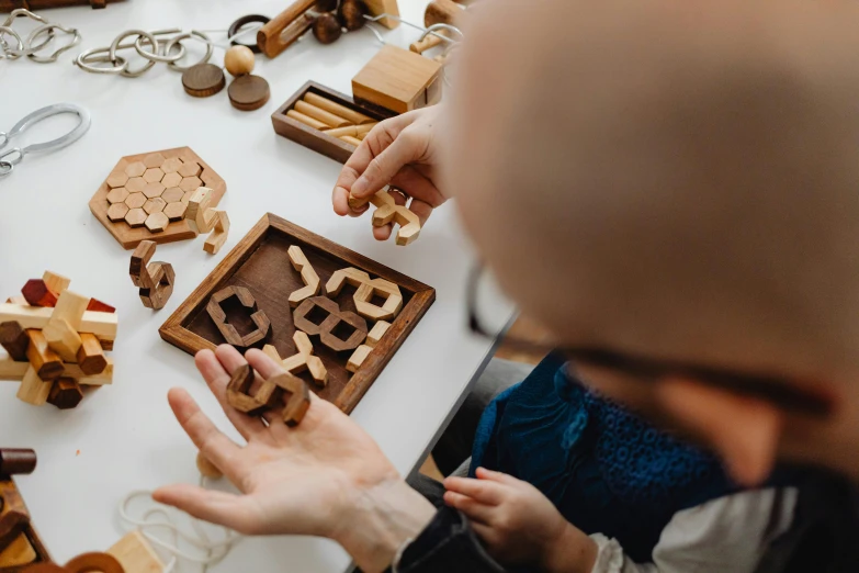 a man playing with wooden toys on a table, a jigsaw puzzle, inspired by Leonardo da Vinci, lost runes, an escape room in a small, jovana rikalo, an intricate