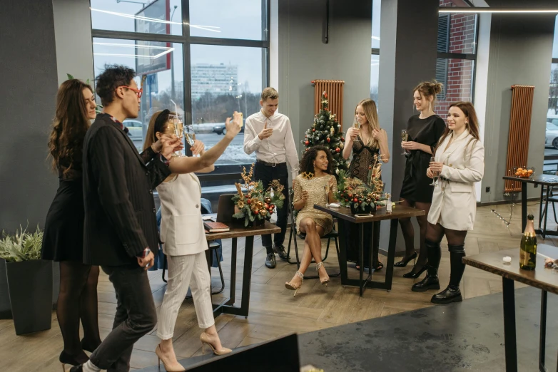 a group of people standing around a table, by Emma Andijewska, pexels contest winner, decorations, office, dancing in the background, lounge