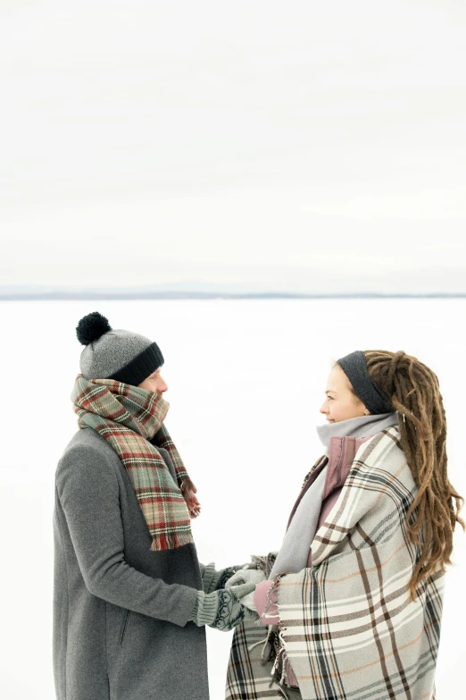 a man and woman holding hands in the snow, tartan scarf, gazing at the water, grey, overlooking