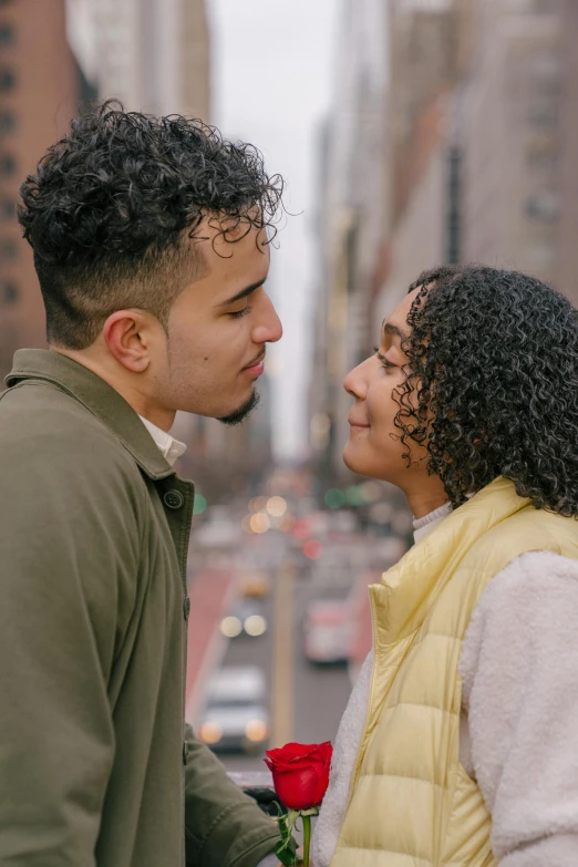 a man standing next to a woman holding a rose, trending on pexels, standing in a city street, third eyes middle of foreheads, mixed race, ( ( theatrical ) )