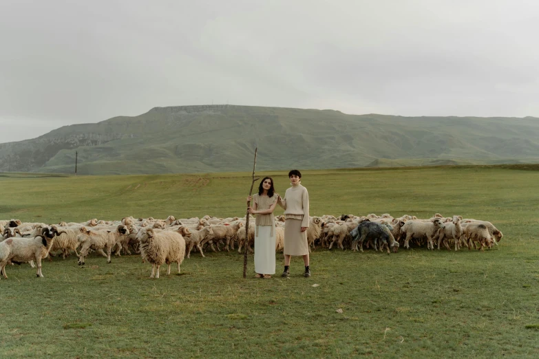 a man standing in front of a herd of sheep, an album cover, inspired by Vanessa Beecroft, renaissance, medium shot of two characters, mongolia, promotional image, ignant