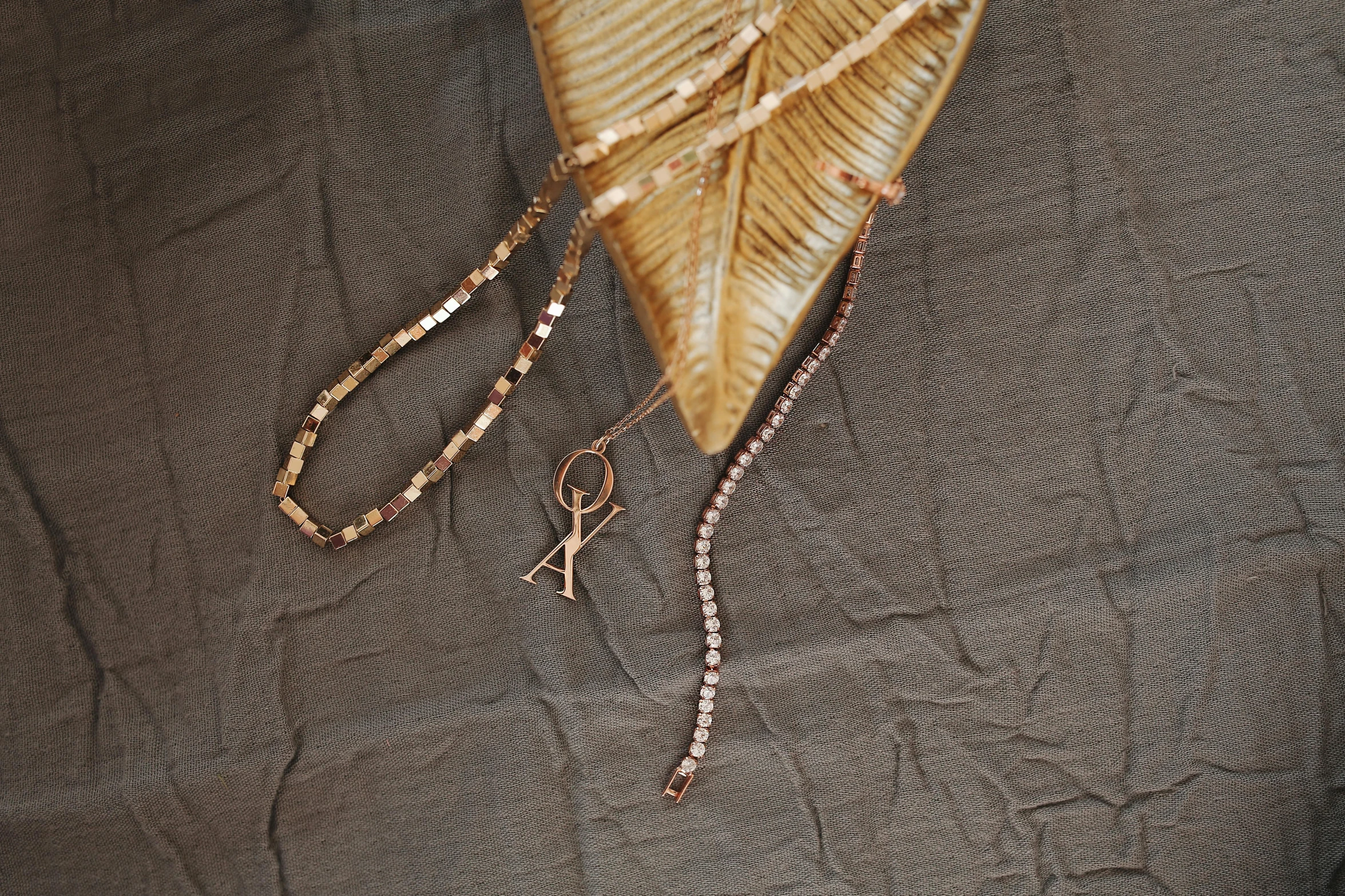 a pair of scissors sitting on top of a piece of cloth, necklace on display, rose gold, sables crossed in background, monika