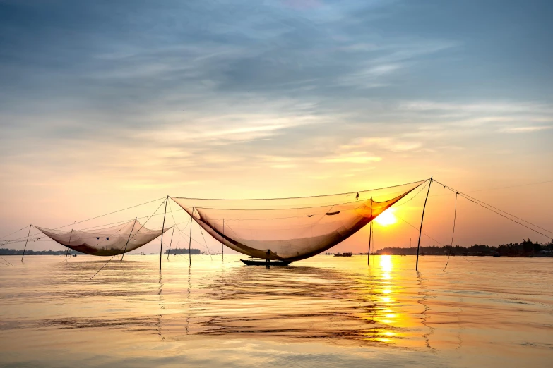 a fishing net sitting on top of a body of water, by Jan Tengnagel, pexels contest winner, silk tarps hanging, asian sun, warm glow, vietnam