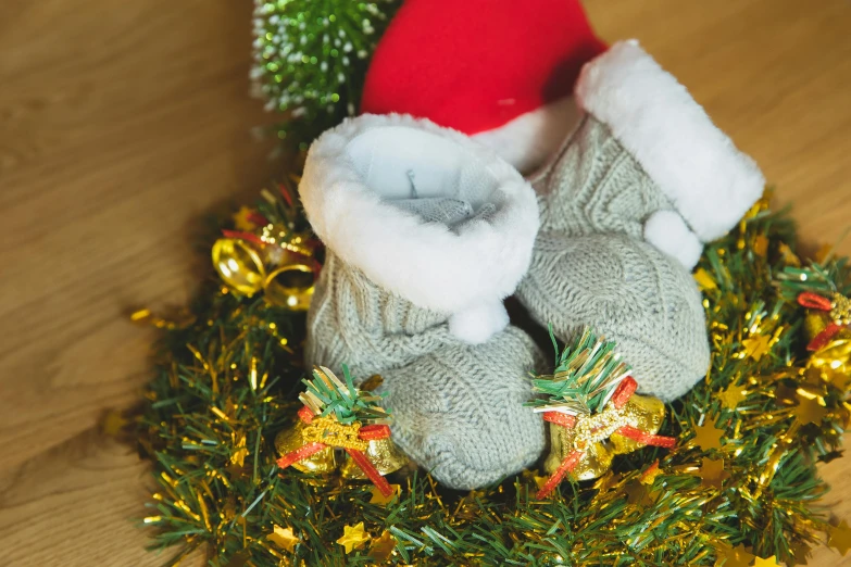 a pair of baby shoes sitting on top of a wreath, pexels, knitted hat, santa's workshop, grey, unfortunate